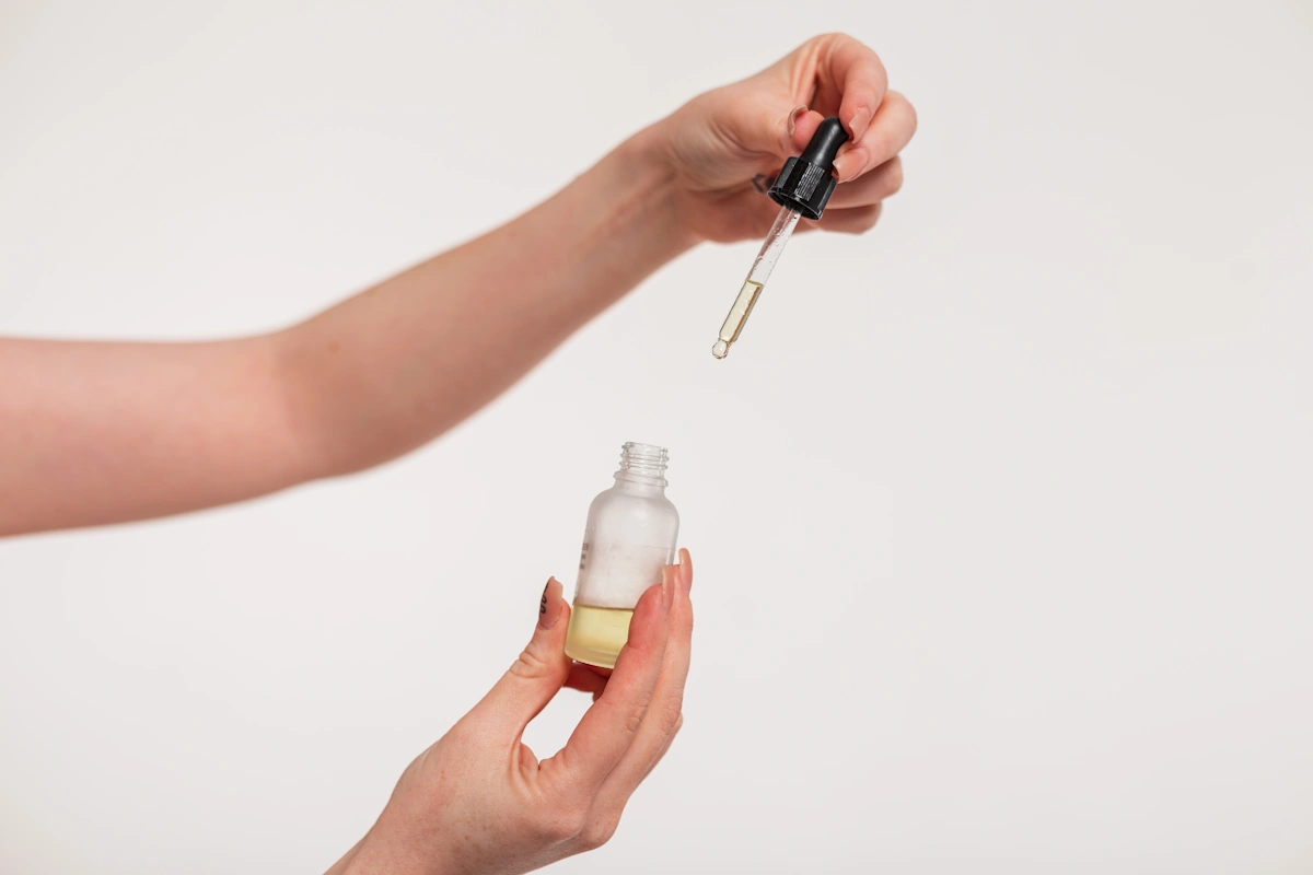 Une personne qui prend  quelques gouttes d'huile de ricin pour les cuticules