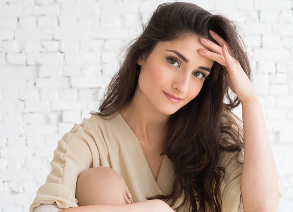 Une femme qui tient un bébé dans ses bras et qui se touche les cheveux