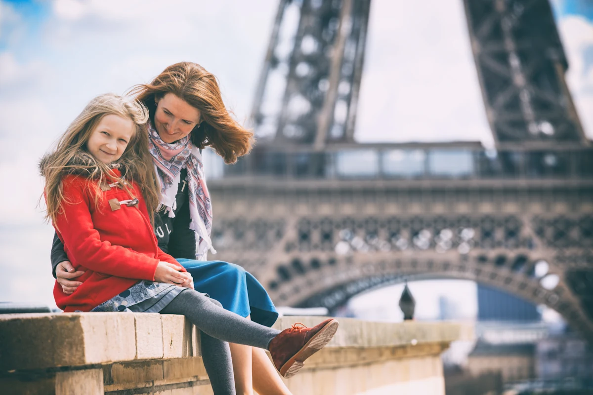 Une femme assise près de la Tour Eiffel avec une petite fille de moins de 6 ans