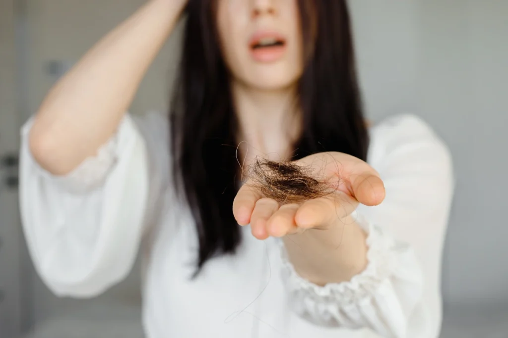 Une femme qui tient dans sa main des chutes de cheveux