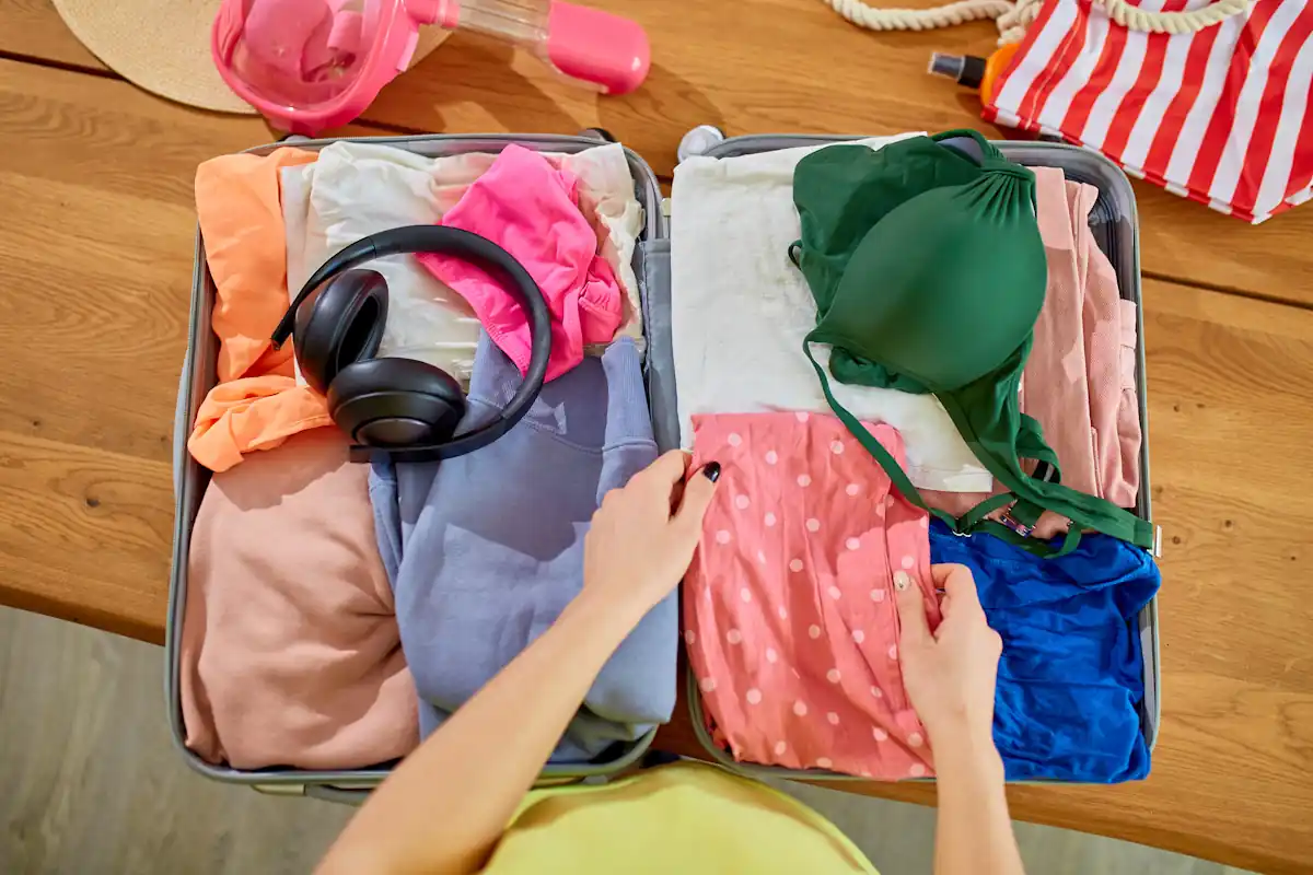 Une personne qui prépare une valise de vêtements